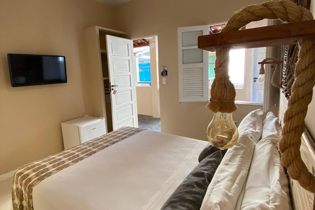 A bedroom with a bed, a TV mounted on the wall, and a door leading to another room.