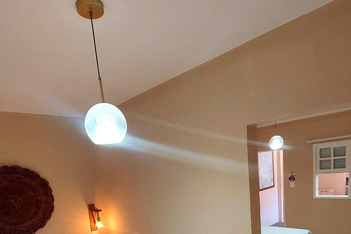 A bedroom with two beds, a wall-mounted light fixture, and a window.
