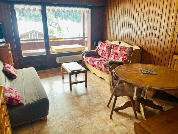 Una habitación acogedora con un sofá, una mesa de madera y un banco.
