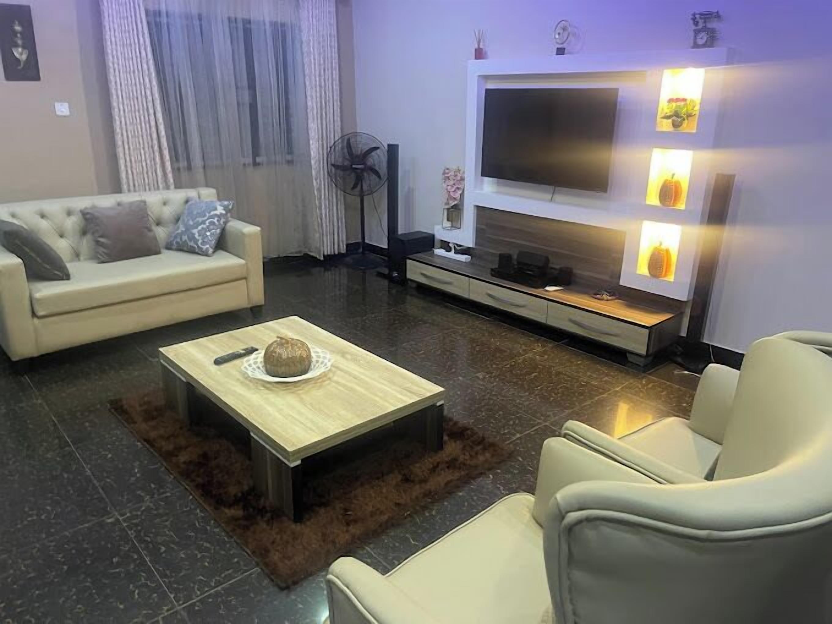 A modern living room with a sofa, a coffee table, a TV, and a fireplace.