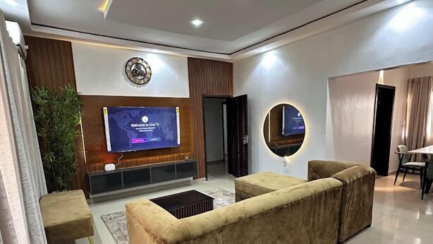 Una sala de estar moderna con televisor de pantalla plana, un espejo redondo y un sofá grande.