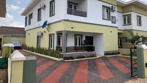 Un edificio residencial de dos plantas con techo plano, un balcón en el piso superior y una antena parabólica en el lateral.