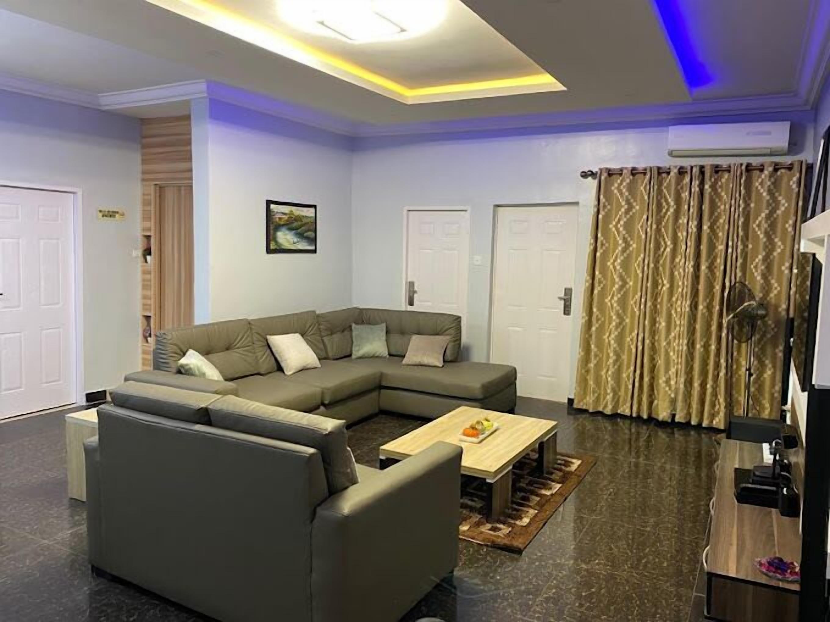 A modern living room with a sectional sofa, a coffee table, and a patterned curtain.