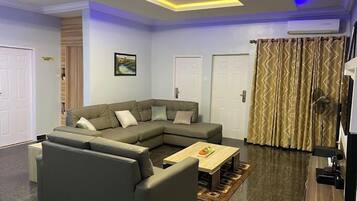 A modern living room with a sectional sofa, a coffee table, and a patterned curtain.