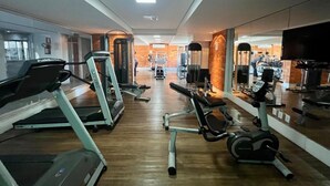 Un gimnasio con cintas de correr, elípticas y bancos de pesas.
