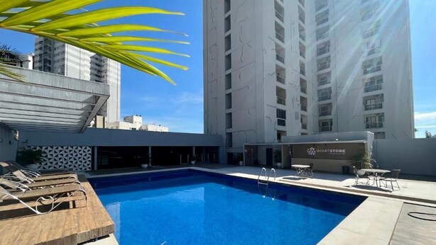 Una piscina con sillas de descanso y un restaurante llamado 'MARISTORE' al fondo.