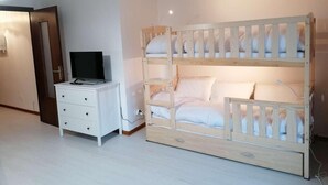 Een kamer met een stapelbed, een witte ladekast en een televisie op de ladekast.