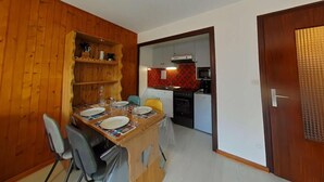 Een kleine keuken met een magnetron, fornuis en een rode, gemønstrede spatwand.