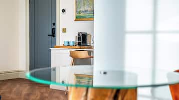Een moderne keuken met een koffieapparaat, een houten stoel en een glazen tafel.