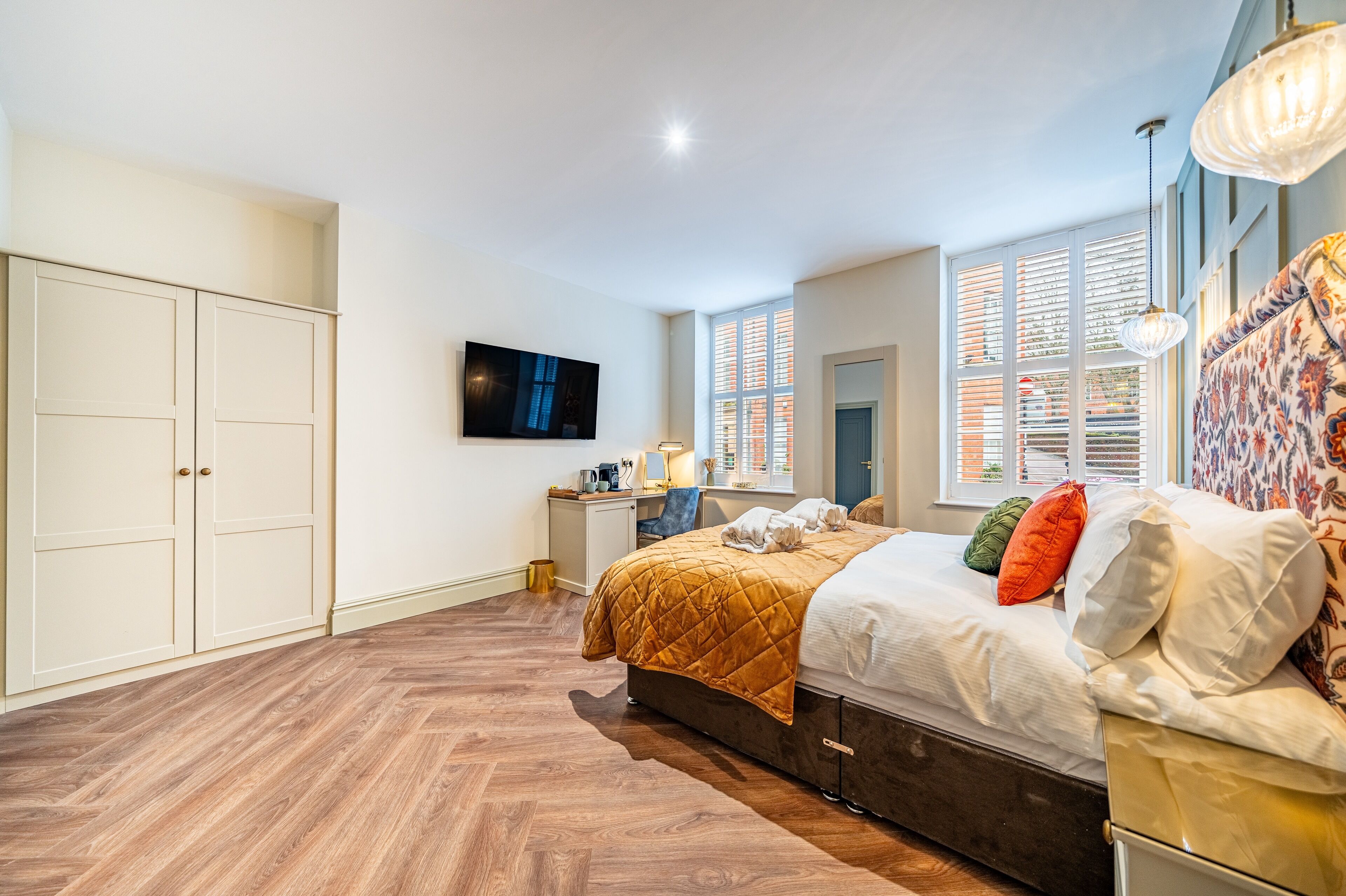 Quarto com cama, escrivaninha, televisão e guarda-roupa.