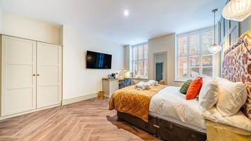 Quarto com cama, escrivaninha, televisão e guarda-roupa.