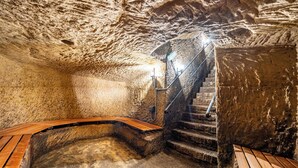 Kövekből épített falak, egy fa pad és egy lépcsőház, amely egy magasabb szintre vezet.