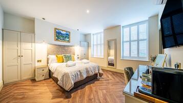 A bedroom with a bed, bedside tables, a TV, and a piano.
