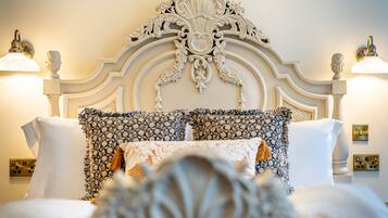 Una cama con un cabecero decorativo, almohadas estampadas y lámparas fijadas a la pared.