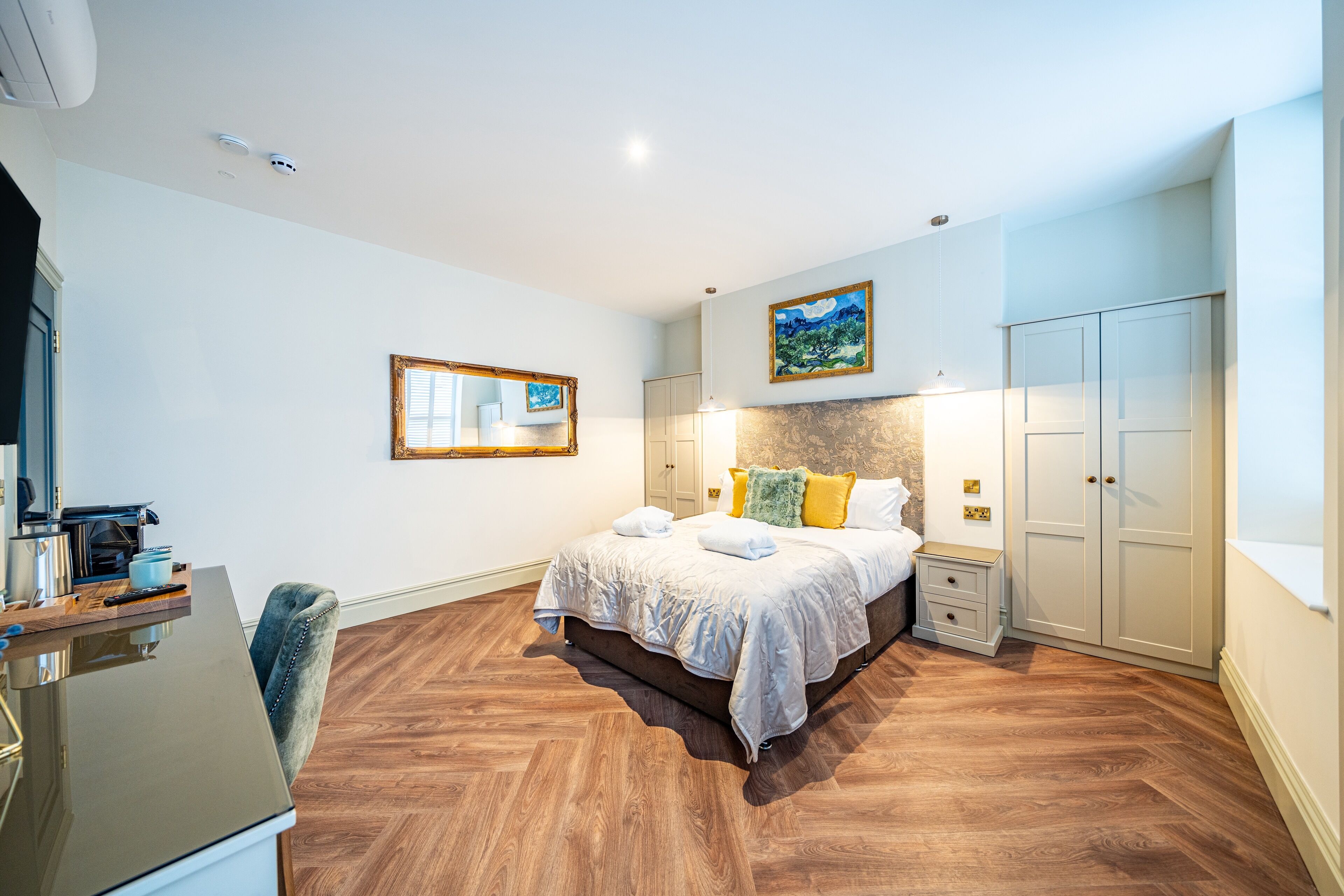 Une chambre à coucher comprenant un lit, des tables de chevet, un bureau et une armoire.