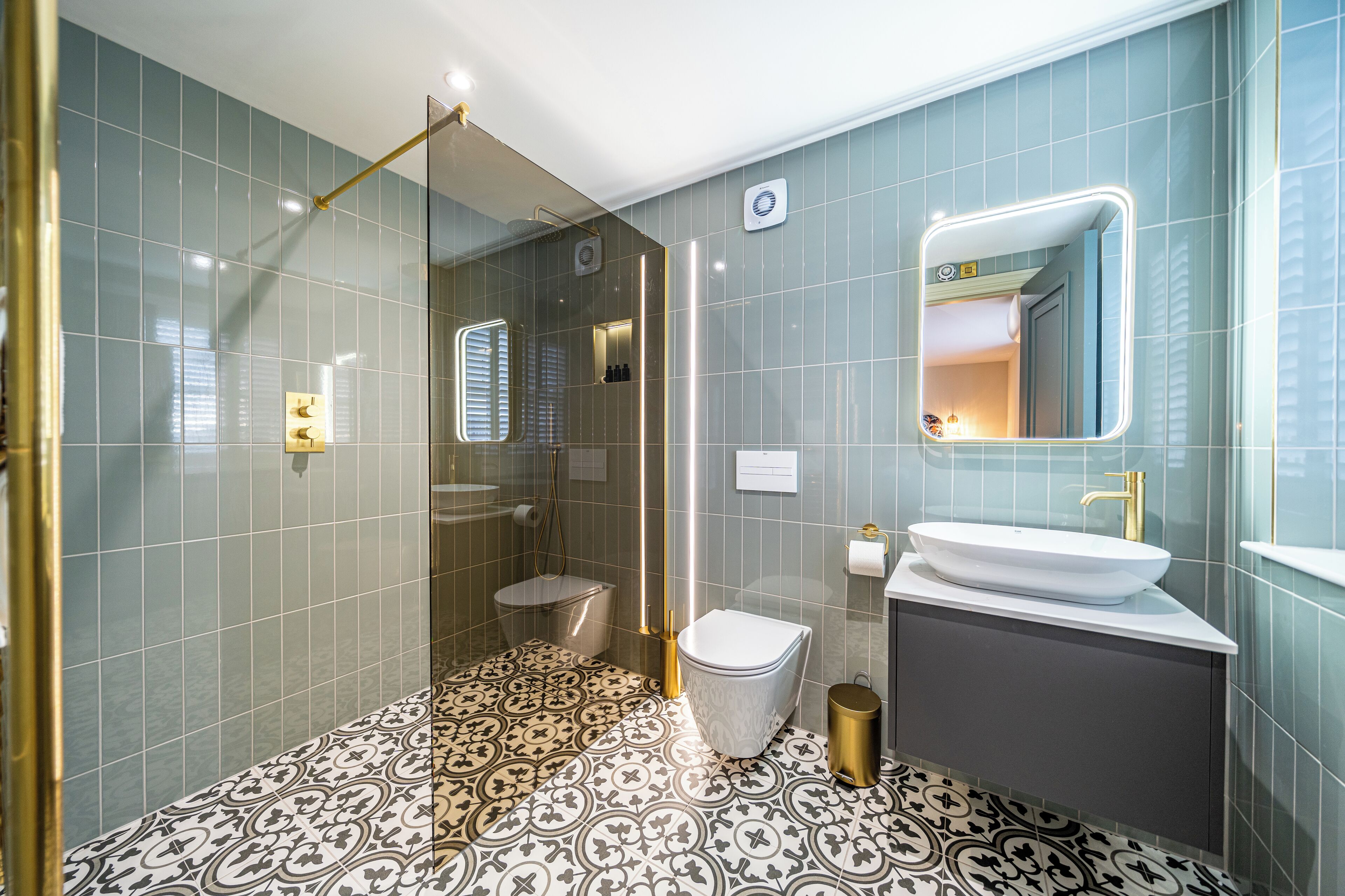 Une salle de bain moderne avec une douche à parois de verre, un lavabo blanc et des carreaux de sol à motifs.