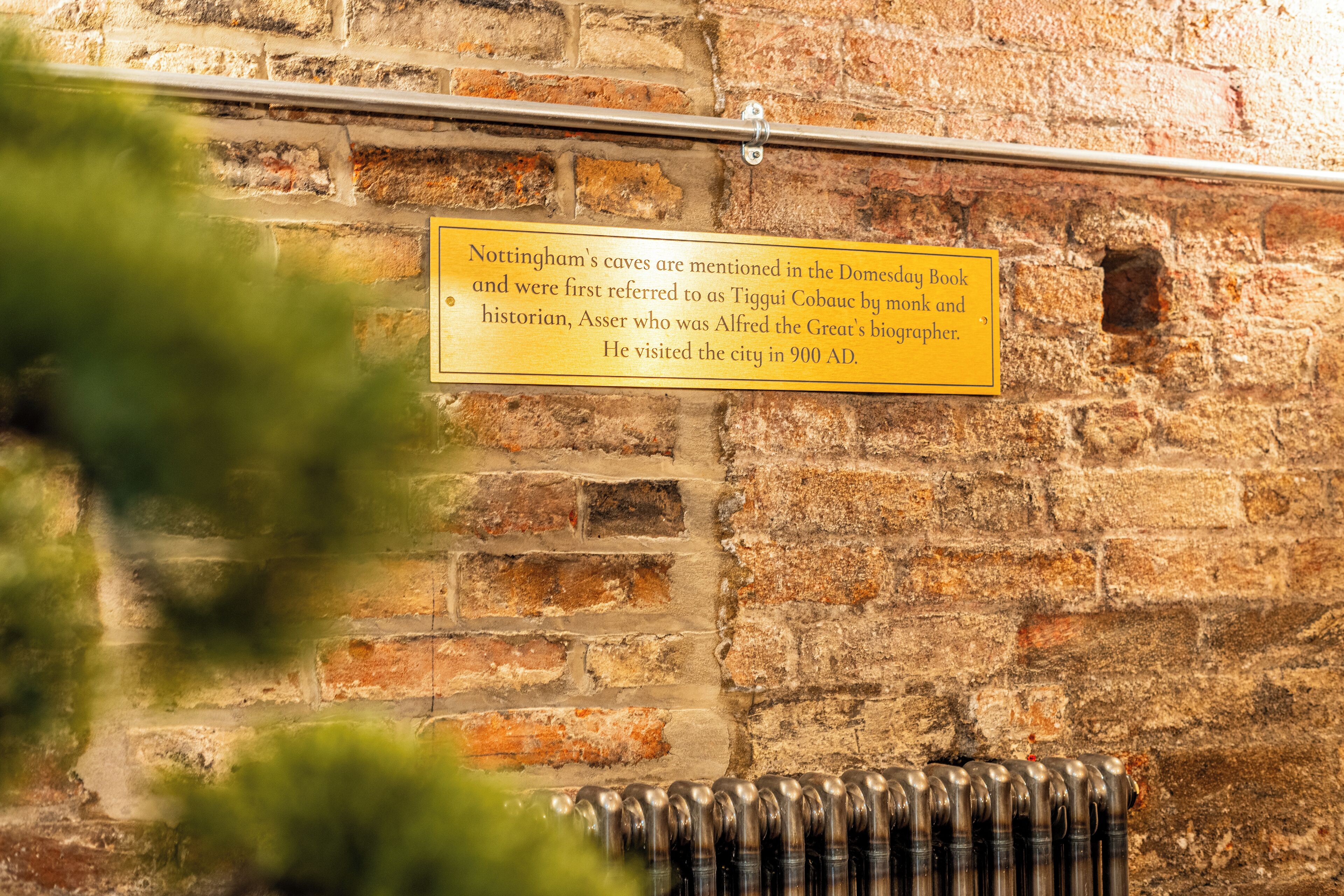Un mur de briques avec une rambarde en métal et une plaque commémorative.