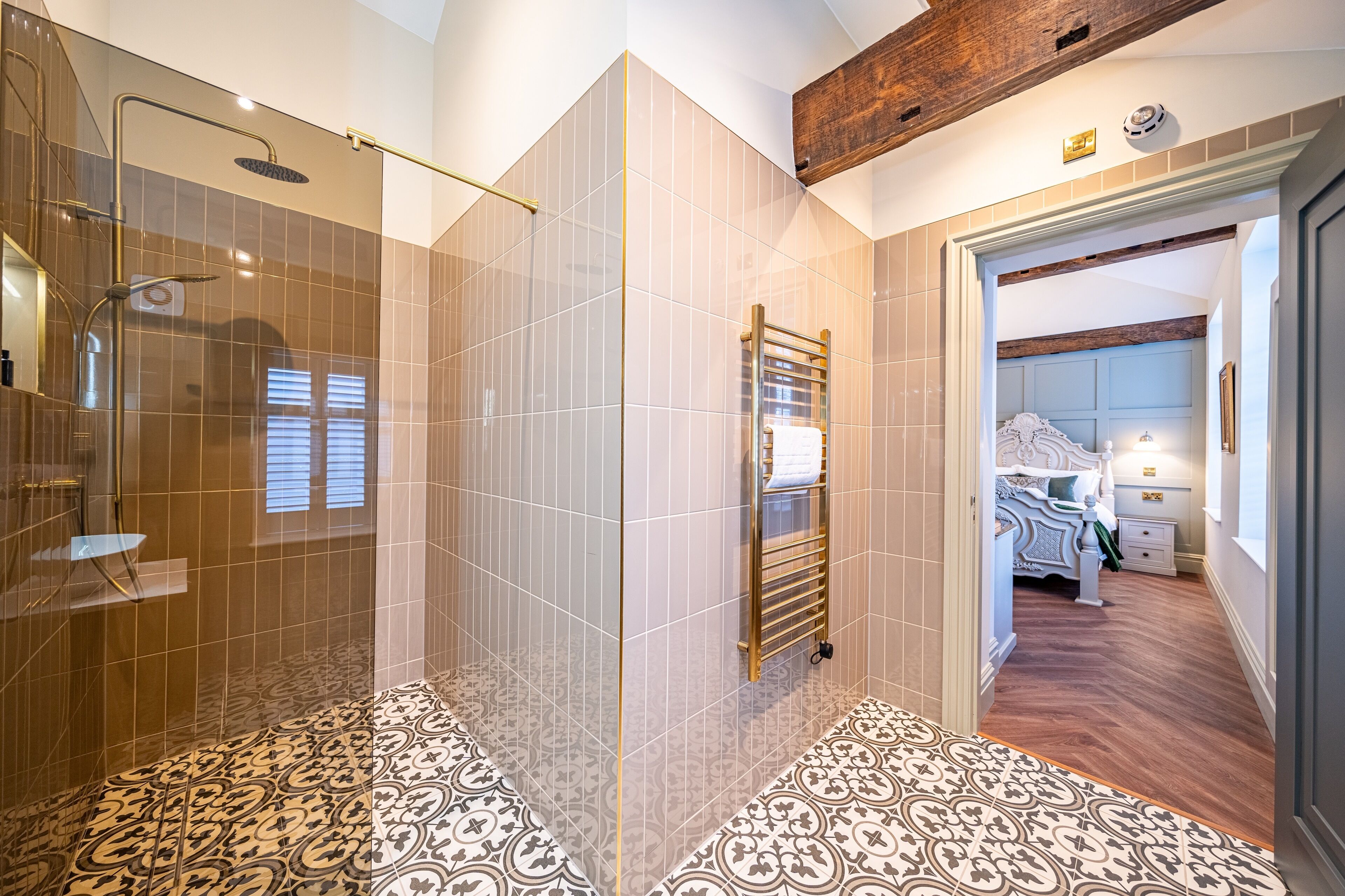A modern bathroom with a shower, a towel rack, and patterned floor tiles.