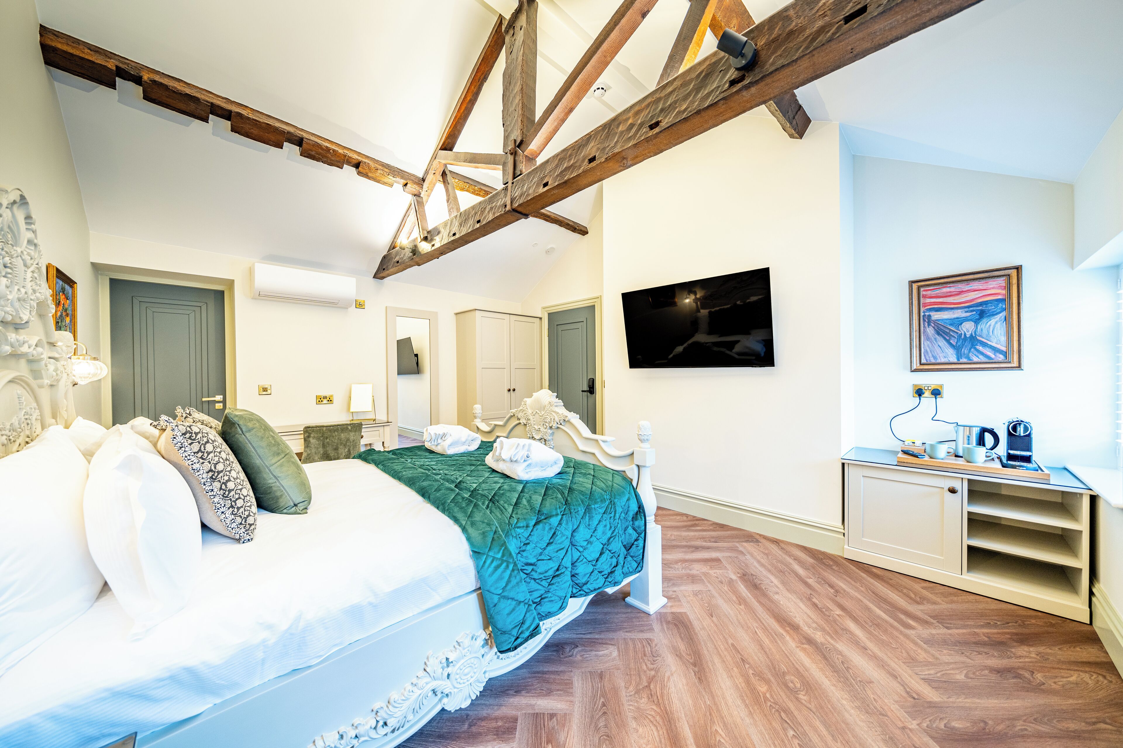 Una camera da letto con un letto, travi in legno, una televisione, un quadro e una piccola credenza.