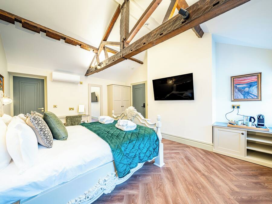 Una camera da letto con un letto, travi in legno, una televisione, un quadro e una piccola credenza.
