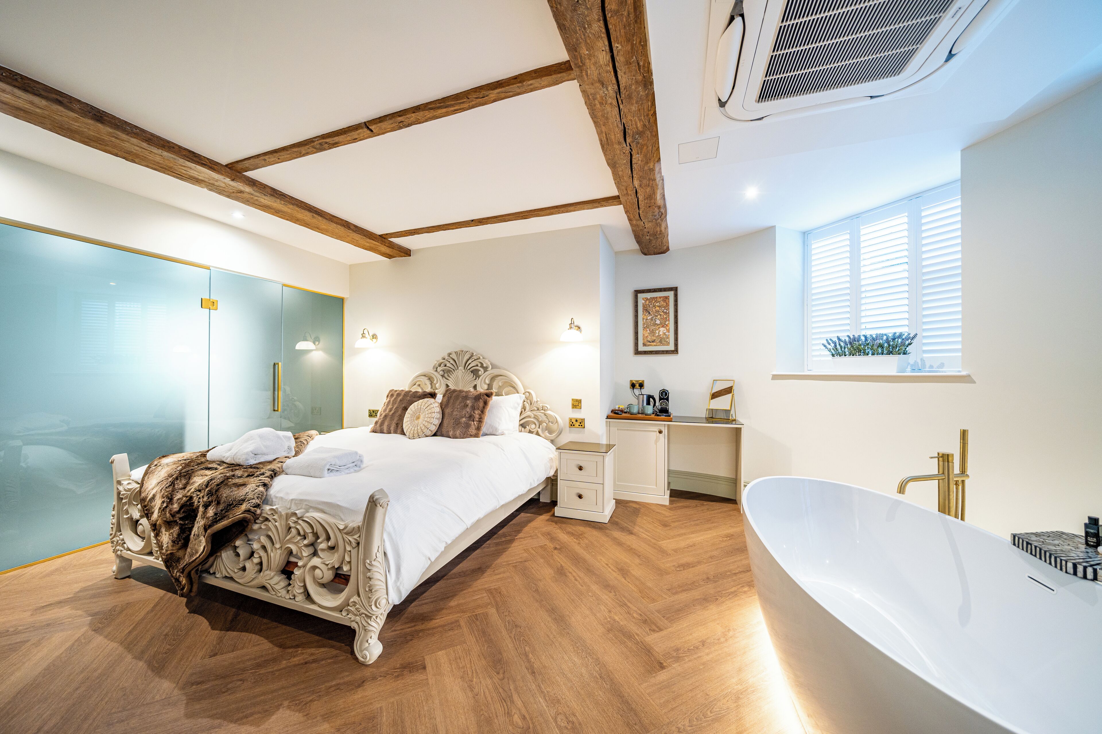 Ein geräumiges Schlafzimmer mit einem großen Bett, einem separaten Schreibtisch, einer Badewanne und einer Duschkabine aus Glas.