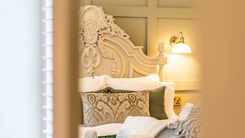 A room with a bed featuring ornate headboard and footboard, a bedside lamp, and a decorative wall panel.