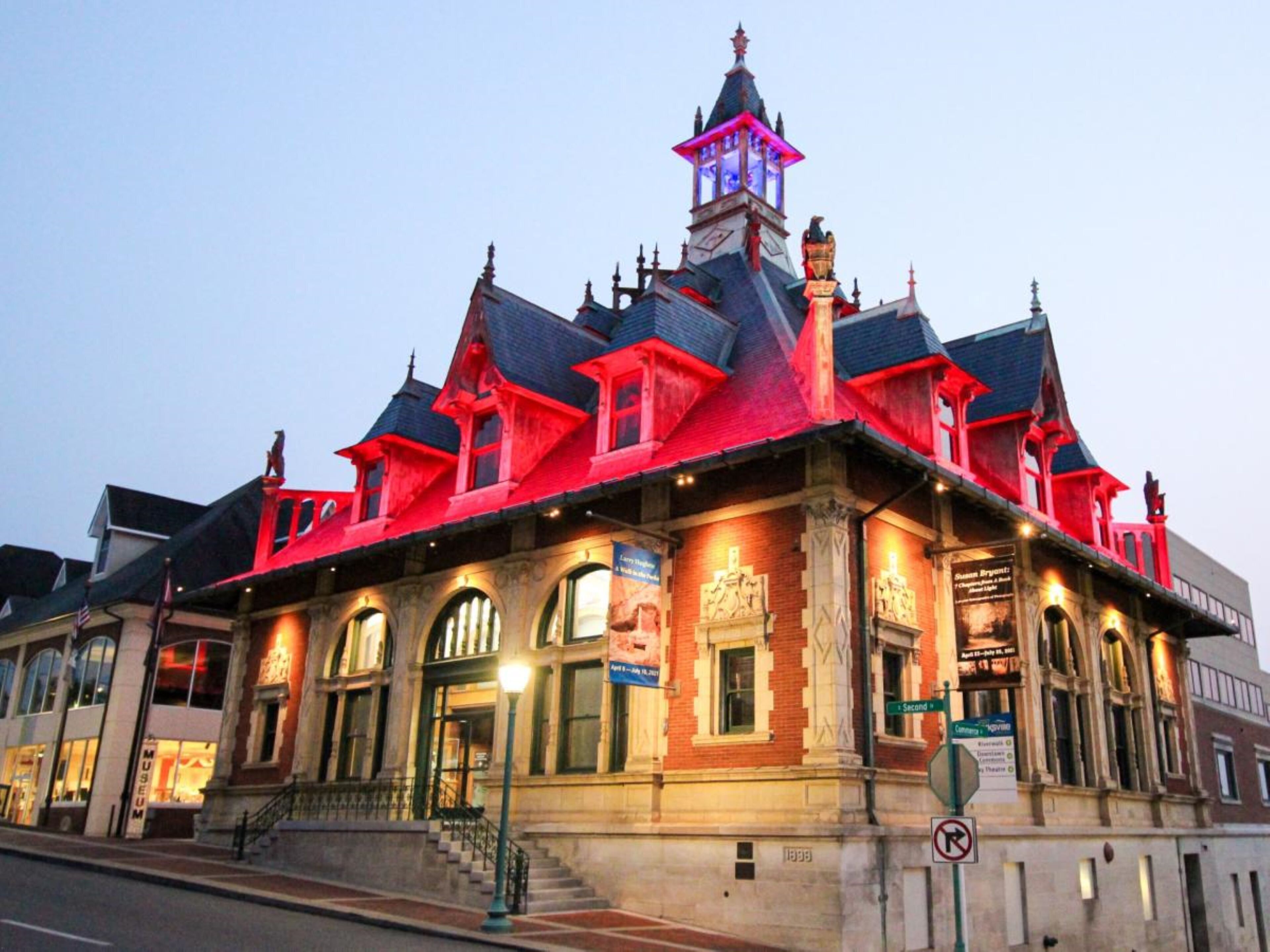 Un edificio histórico con una destacada torre de reloj, ventanas arqueadas y un techo rojo.
