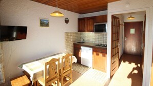 A compact kitchen with wooden cabinets, a tiled backsplash, and a built-in microwave.