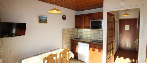 A compact kitchen with wooden cabinets, a tiled backsplash, and a built-in microwave.