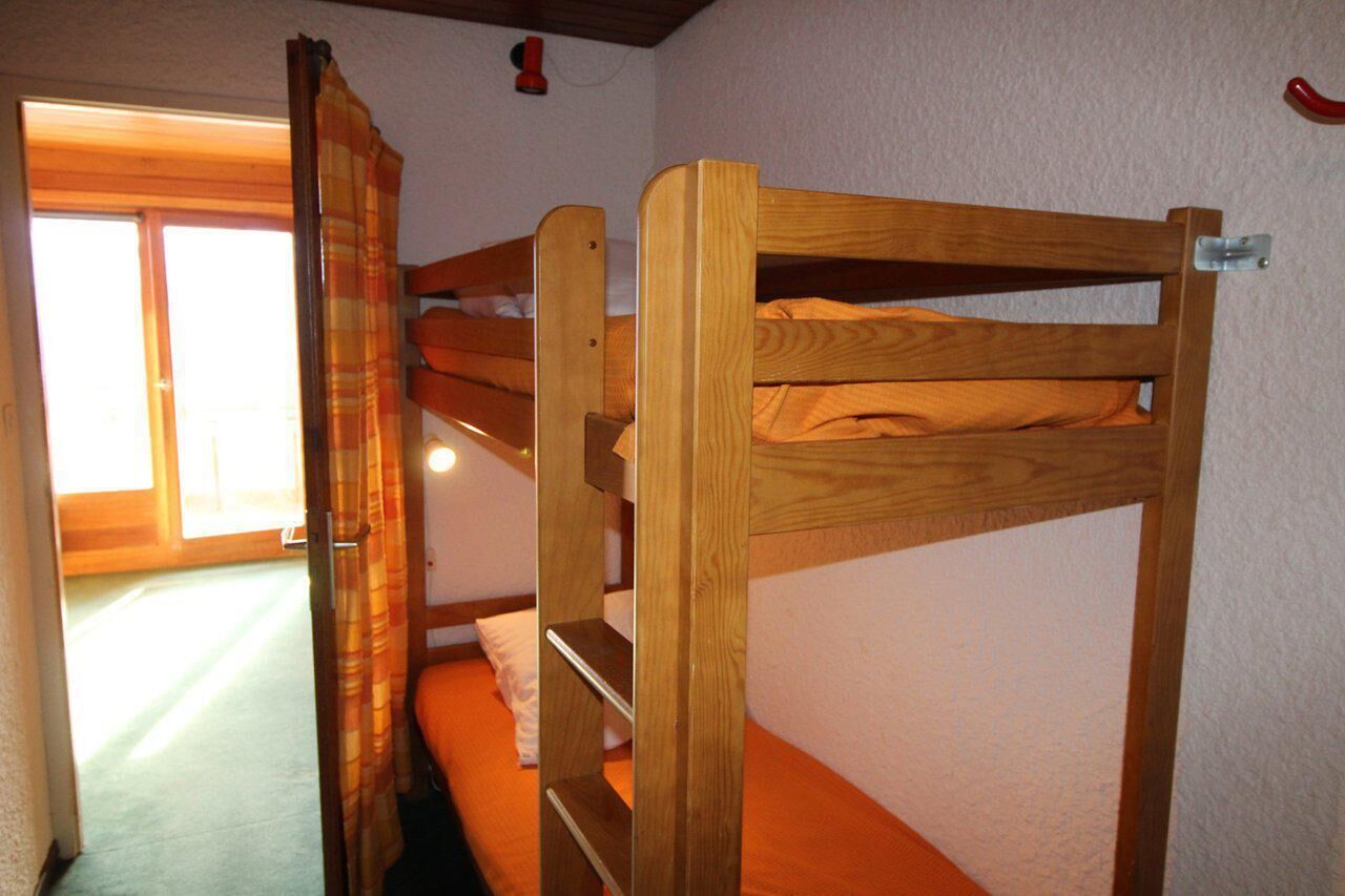 A bunk bed in a room with a window and a curtain.