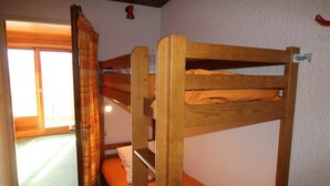 Een stapelbed in een kamer met een raam en een gordijn.