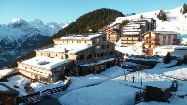 Een bergstad bedekt met sneeuw, met gebouwen, een skigebied en een restaurantgedeelte.