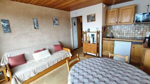 Une pièce confortable comprenant un lit, un canapé, une table à manger, des meubles en bois et un coin cuisine équipé d’un four à micro-ondes et d’un réfrigérateur.