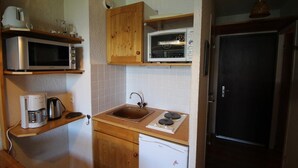 A compact kitchen with a microwave, toaster oven, coffee maker, sink, and a small refrigerator. - 300m from ski slopes, Ground floor, view valley, balcony, tv, ski locker, 19m², Auris en Oisans (Auris)