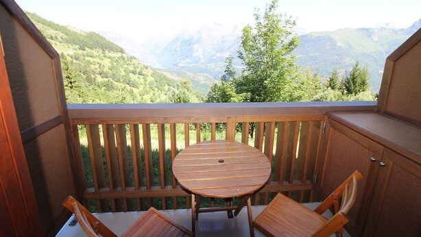 A wooden deck with a round table and two chairs, overlooking a mountainous landscape. - 300m from ski slopes, Ground floor, view valley, balcony, tv, ski locker, 19m², Auris en Oisans (Auris)