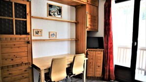 Een houten eethoek met een tafel en stoelen, een televisie en een schuifdeur met uitzicht.