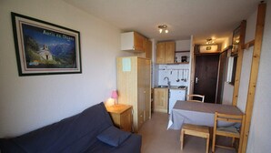 A compact room with a sofa, a small dining table with chairs, a kitchenette, and a framed picture on the wall. - 300m from ski slopes, 2nd floor, view mountain, balcony, tv, ski locker, 17m², Auris en Oisans (Auris)