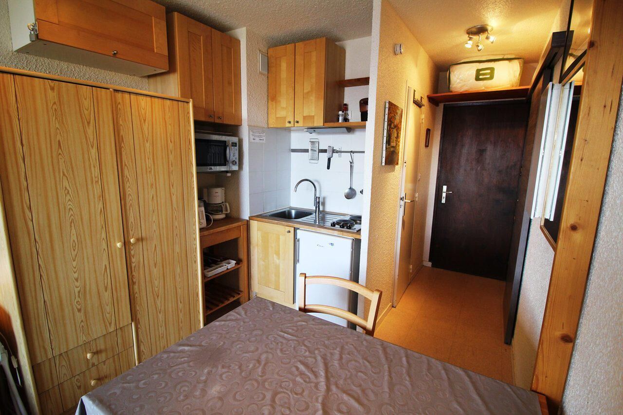 Une cuisine compacte avec des meubles de rangement en bois, un four à micro-ondes, un évier et un petit réfrigérateur.