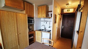 A compact kitchen with wooden cabinets, a microwave, a sink, and a small refrigerator. - 300m from ski slopes, 2nd floor, view mountain, balcony, tv, ski locker, 17m², Auris en Oisans (Auris)