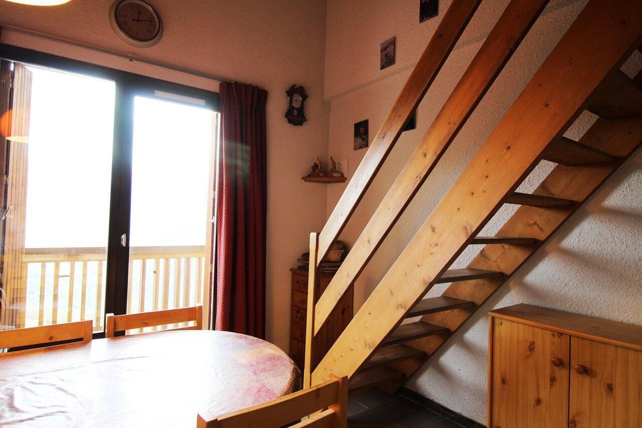 A room with a wooden staircase, a table, and a bed.