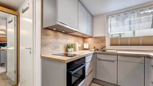 Una cucina moderna con forno integrato, lavello e finestra con persiane.