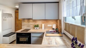 Una cucina moderna con piano di lavoro in legno, elettrodomestici integrati e una finestra con persiane.