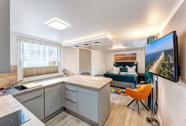 Cozy apartment with a kitchenette, dining area, and living space featuring a sofa, flat-screen TV, and sink.