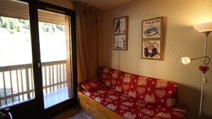 A cozy room with a wooden bench, a sliding glass door, and wall art. - 300m from ski slopes, view mountain/swimming pool, balcony, tv, ski locker, 17m², Auris en Oisans (Auris)