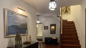 A staircase with wooden steps leading to a landing, a framed painting on the wall, and a decorative lantern on a dresser.