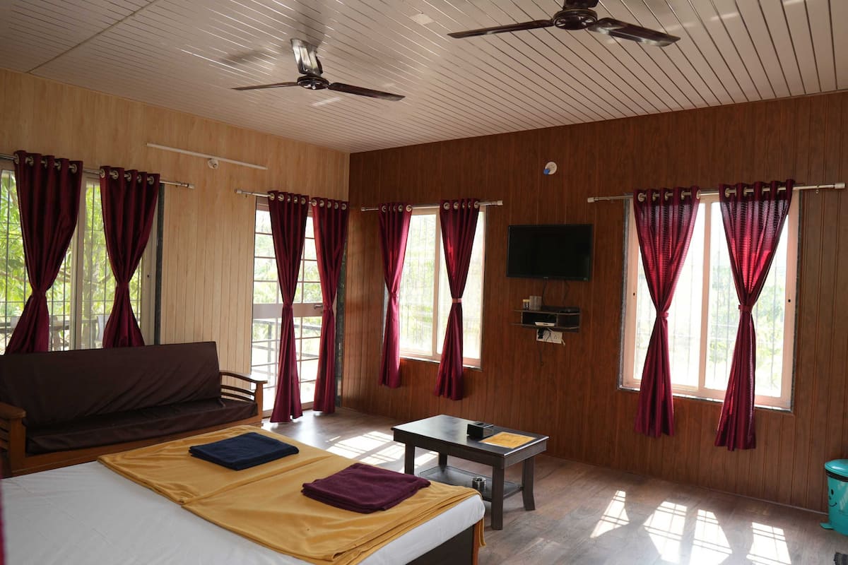 A room with a bed, a sofa, a table, and a TV.