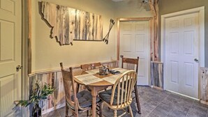Un coin repas avec une table et des chaises en bois, une carte accrochée au mur et un ventilateur de plafond.