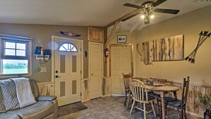 Un salon confortable avec un canapé, une table à manger et des chaises, un ventilateur de plafond et une fenêtre avec des stores.