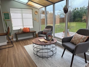 Ein gemütliches Wohnzimmer mit einem runden Couchtisch, bequemen Sitzgelegenheiten und einem großen Fenster mit Blick ins Freie.