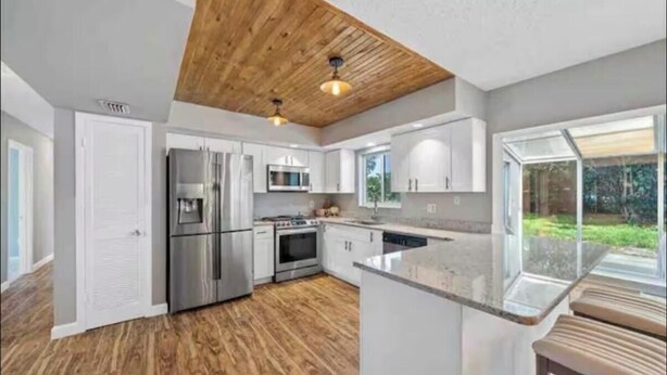 Een moderne keuken met houten plafond, roestvrijstalen apparatuur en een groot eiland.